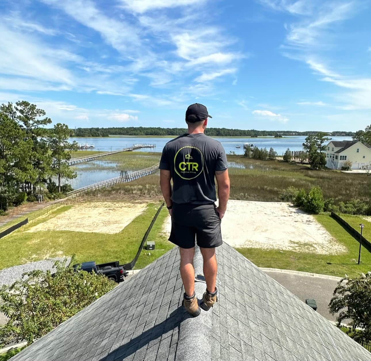 man standing on roof looking into lake